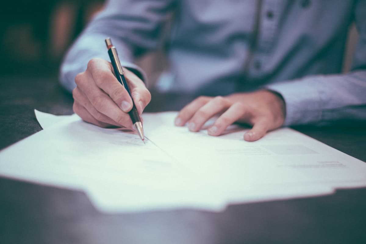 A person signing a stack of documents at a desk