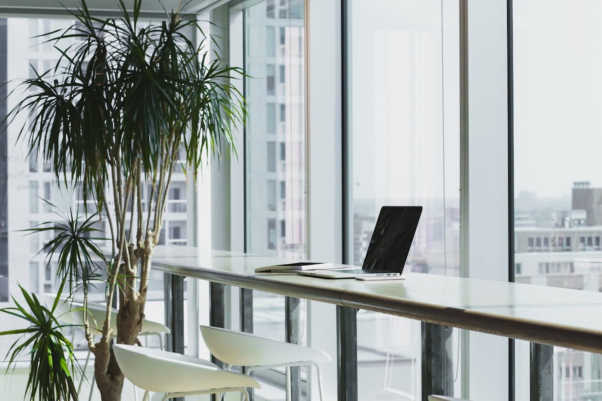 A bright office with a long desk beside floor-to-ceiling windows