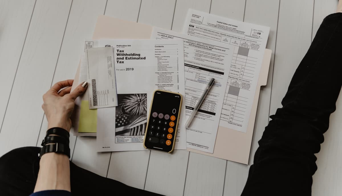 Tax paperwork, a calculator and a pen laid out on a desk